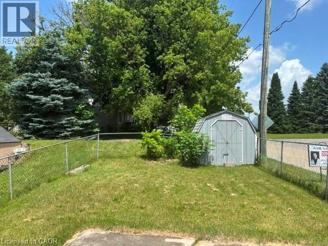 Fenced yard featuring a gray storage shed and mature trees - 13 Second Avenue E, Simcoe, ON - Outdoor
