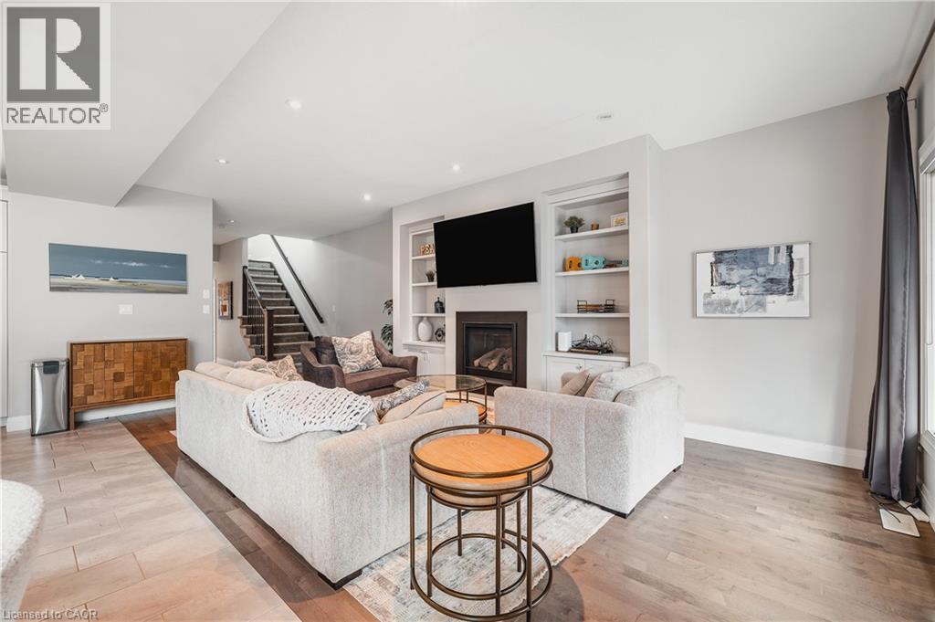 Living room with a glass covered fireplace, light wood-style flooring, built in features, stairway, and recessed lighting - 346 Moorlands Crescent, Kitchener, ON - Indoor Photo Showing Living Room With Fireplace