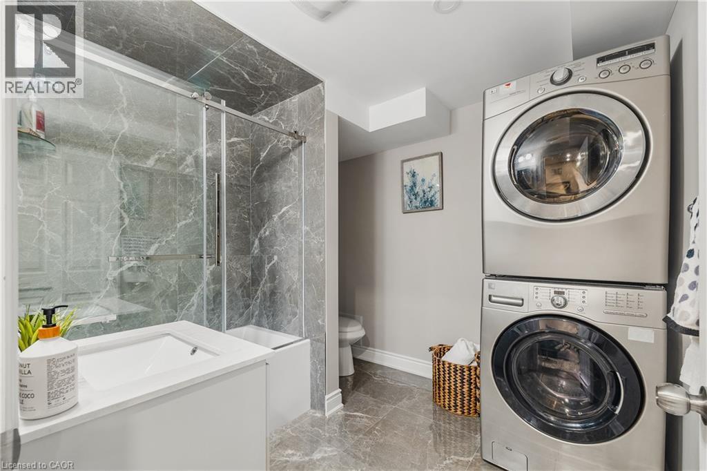 Full bathroom featuring light marble finish flooring, stacked washer / drying machine, a marble finish shower, and vanity - 346 Moorlands Crescent, Kitchener, ON - Indoor Photo Showing Laundry Room