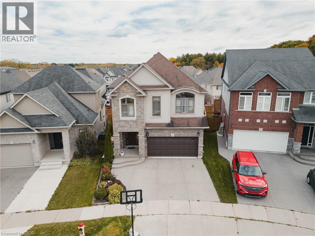 View of front facade with driveway, a residential view, stone siding, an attached garage, and roof with shingles - 346 Moorlands Crescent, Kitchener, ON - Outdoor With Facade
