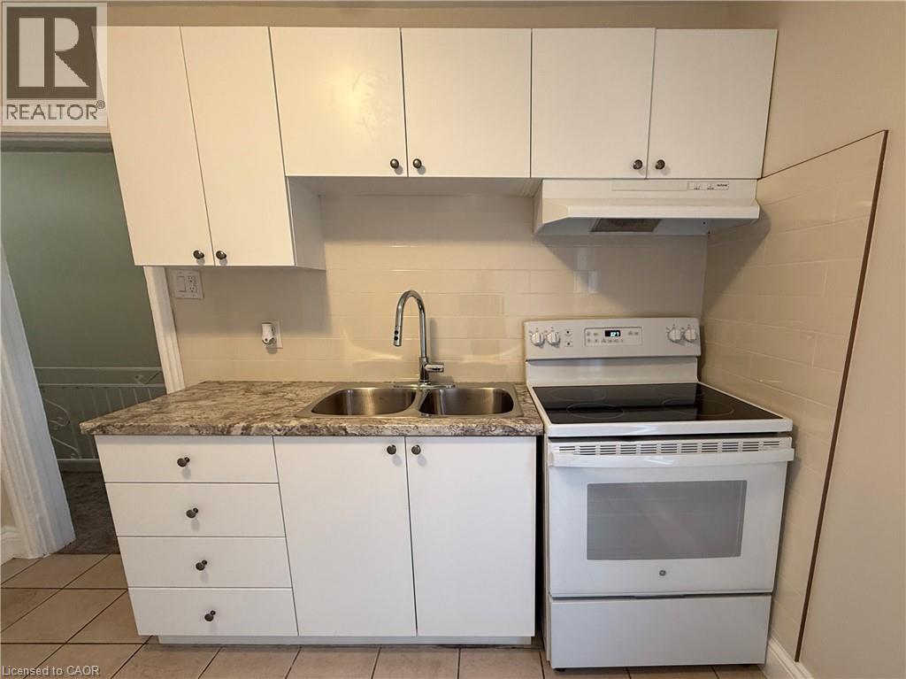 Kitchen featuring electric range, light countertops, white cabinetry, and light tile patterned floors - 24 Somerset Avenue, Hamilton, ON - Indoor Photo Showing Kitchen With Double Sink