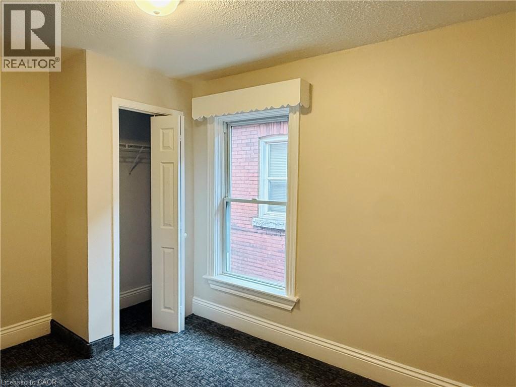 Unfurnished bedroom featuring a textured ceiling, a closet, and dark colored carpet - 24 Somerset Avenue, Hamilton, ON - Indoor Photo Showing Other Room