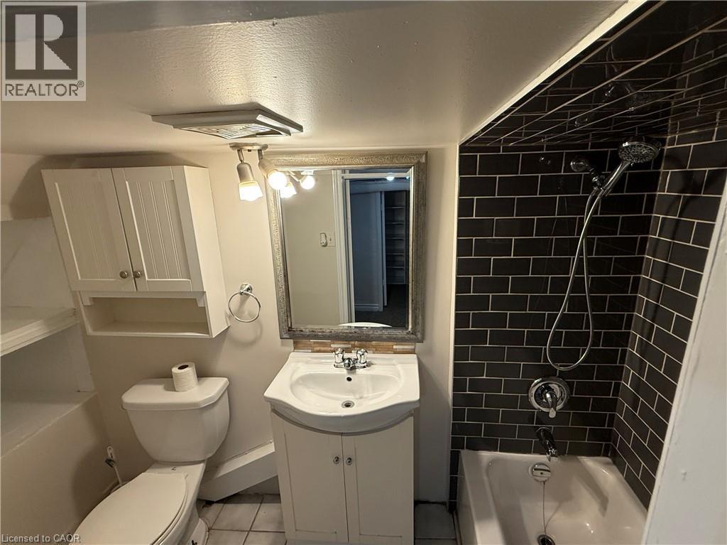 Bathroom featuring bathing tub / shower combination, vanity, a textured ceiling, and tile patterned flooring - 24 Somerset Avenue, Hamilton, ON - Indoor Photo Showing Bathroom
