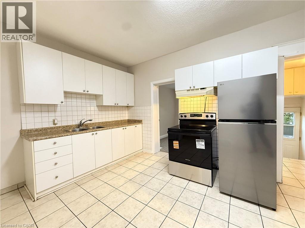 Kitchen featuring appliances with stainless steel finishes, backsplash, dark countertops, and white cabinetry - 24 Somerset Avenue, Hamilton, ON - Indoor Photo Showing Kitchen With Double Sink