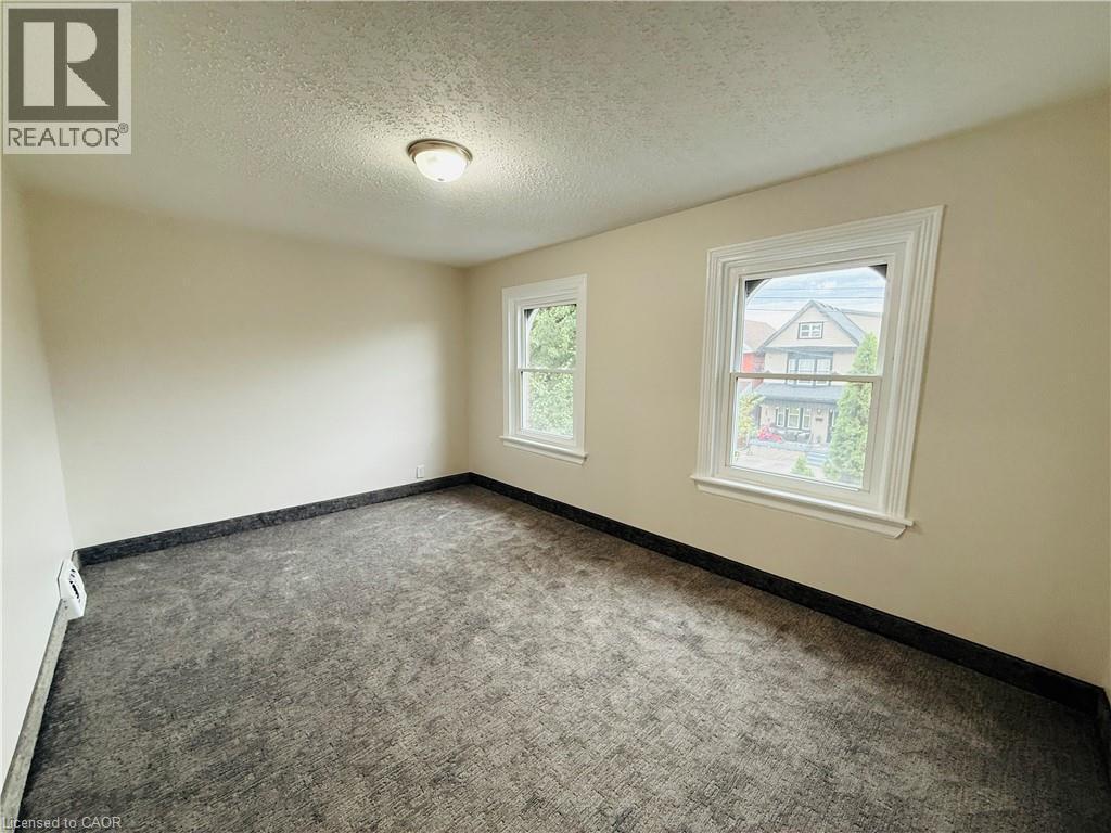 Carpeted spare room featuring a textured ceiling and a baseboard heating unit - 24 Somerset Avenue, Hamilton, ON - Indoor Photo Showing Other Room