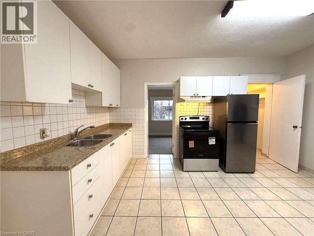 Kitchen with stainless steel appliances, white cabinets, backsplash, light tile patterned floors, and a textured ceiling - 24 Somerset Avenue, Hamilton, ON - Indoor Photo Showing Kitchen With Double Sink