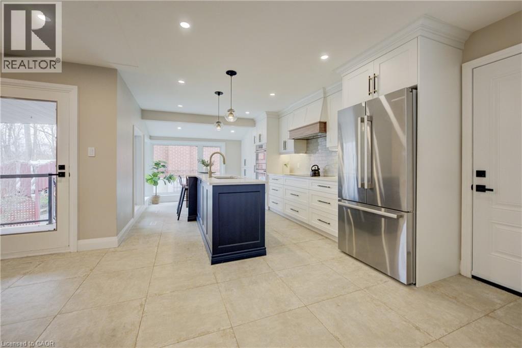 Kitchen featuring freestanding refrigerator, white cabinets, an island with sink, hanging light fixtures, and tasteful backsplash - 279 Ferndale Place, Waterloo, ON - Indoor Photo Showing Kitchen With Upgraded Kitchen