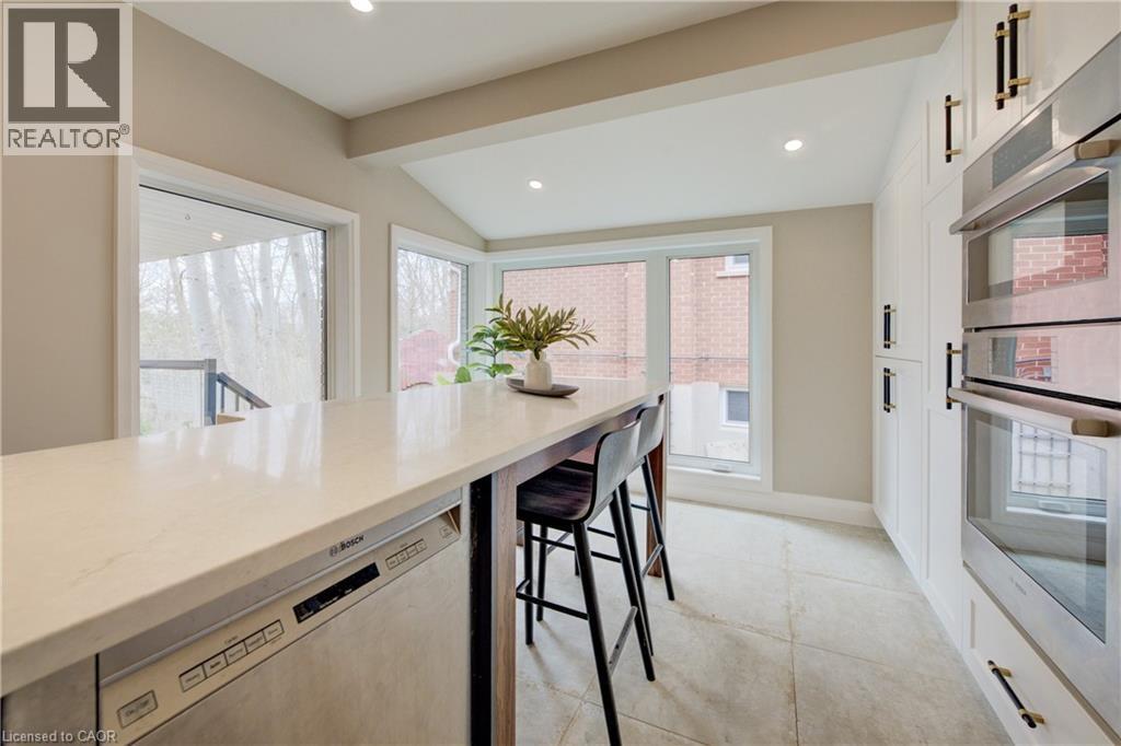 Kitchen featuring stainless steel appliances, light stone counters, vaulted ceiling, recessed lighting, and plenty of natural light - 279 Ferndale Place, Waterloo, ON - Indoor