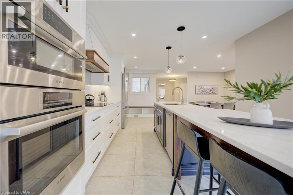Kitchen featuring appliances with stainless steel finishes, white cabinets, decorative light fixtures, light stone counters, and recessed lighting - 279 Ferndale Place, Waterloo, ON - Indoor Photo Showing Kitchen With Upgraded Kitchen