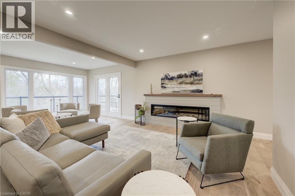 Living room with a glass covered fireplace, wood finished floors, recessed lighting, and beam ceiling - 279 Ferndale Place, Waterloo, ON - Indoor Photo Showing Living Room With Fireplace