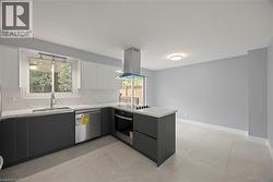 Kitchen with modern cabinets, a peninsula, decorative backsplash, oven, and island range hood -