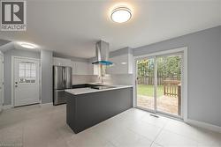 Kitchen with freestanding refrigerator, light countertops, white cabinets, island range hood, and a peninsula -