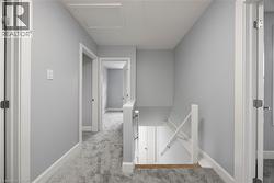 Hallway featuring an upstairs landing, carpet, and attic access -