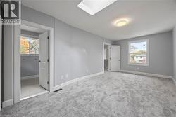 Unfurnished bedroom with a skylight, light colored carpet, and connected bathroom -
