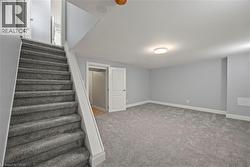 Finished basement featuring stairway and light colored carpet -