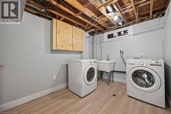 Laundry area with light wood-type flooring, washer and dryer, and cabinet space -