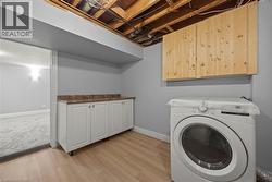 Laundry area featuring washer / clothes dryer, light wood finished floors, and cabinet space -