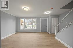 Foyer entrance with light wood-style flooring, ornamental molding, and stairway -
