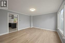 Empty room featuring light wood-type flooring and crown molding -