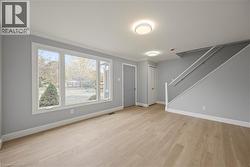 Unfurnished living room featuring crown molding, light wood-style floors, and stairs -