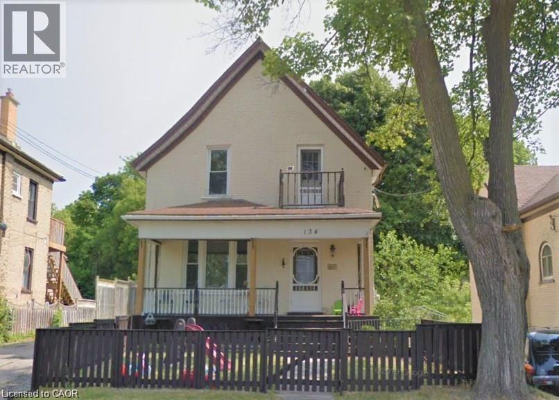 View of front of house with a fenced front yard, a porch, and a balcony - 134 Courtland Avenue E, Kitchener, ON