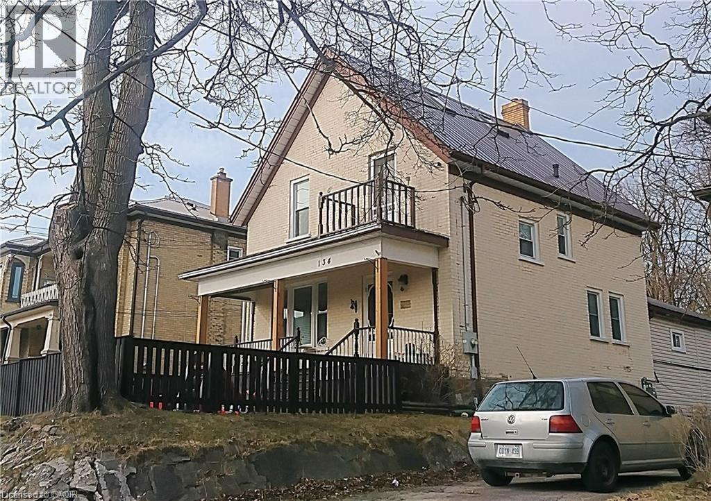 View of property exterior with brick siding, a chimney, covered porch, and a balcony - 134 Courtland Avenue E, Kitchener, ON