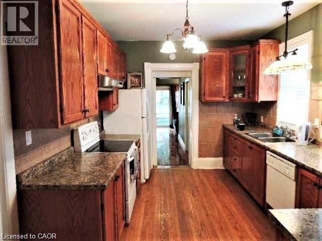 Kitchen with white appliances, dark wood-type flooring, a chandelier, and pendant lighting - 134 Courtland Avenue E, Kitchener, ON