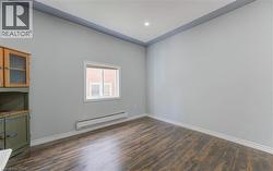 Unfurnished room with a baseboard heating unit, dark wood-style floors, and recessed lighting -
