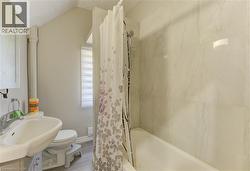Bathroom featuring shower / bath combination with curtain, vanity, vaulted ceiling, and wood finished floors -