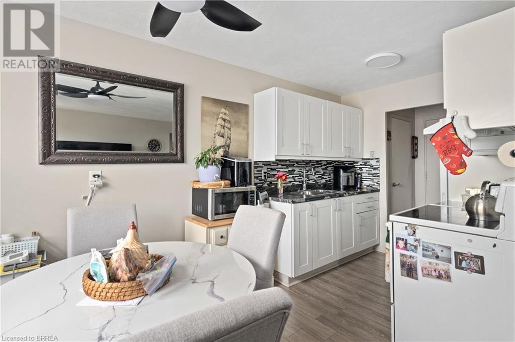 Kitchen with stainless steel microwave, a ceiling fan, backsplash, a sink, and wood finished floors - 485 Thorold Road Unit# 323, Welland, ON - Indoor