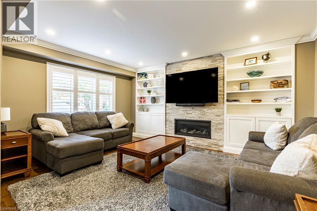 Living room featuring ornamental molding, a stone fireplace, wood finished floors, and recessed lighting - 28 Springbreeze Heights, Hamilton, ON - Indoor Photo Showing Living Room With Fireplace