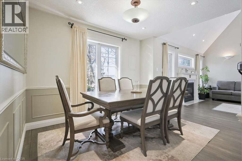 Dining room with a fireplace with flush hearth, dark wood-style flooring, lofted ceiling, a decorative wall, and wainscoting - 629 Burning Bush Road, Waterloo, ON - Indoor Photo Showing Dining Room