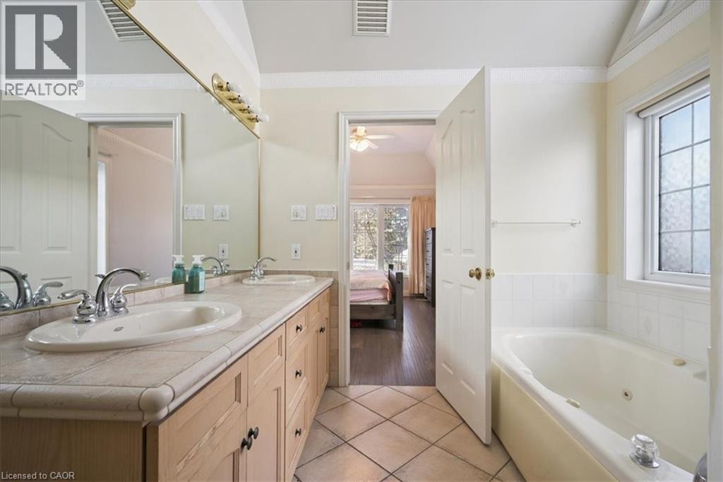 Full bathroom featuring double vanity, a whirlpool tub, connected bathroom, light tile patterned floors, and ornamental molding - 629 Burning Bush Road, Waterloo, ON - Indoor Photo Showing Bathroom