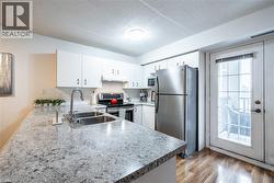 Kitchen with appliances with stainless steel finishes, a peninsula, light countertops, white cabinetry, and light wood-style flooring -