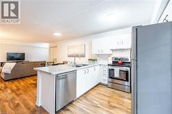 Kitchen featuring appliances with stainless steel finishes, white cabinets, light countertops, a peninsula, and open floor plan -