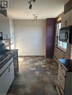 Kitchen featuring track lighting, brick wall, dishwashing machine, sink, and white cabinets -