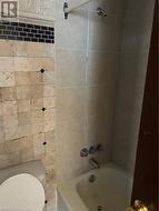 Bathroom featuring toilet and tiled shower / bath -