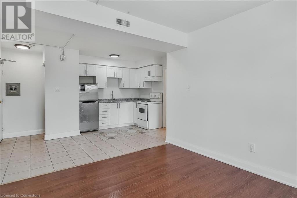 Kitchen featuring white range oven, freestanding refrigerator, white cabinetry, light wood-style flooring, and under cabinet range hood - 897 Barton Street E, Hamilton, ON - Indoor Photo Showing Kitchen
