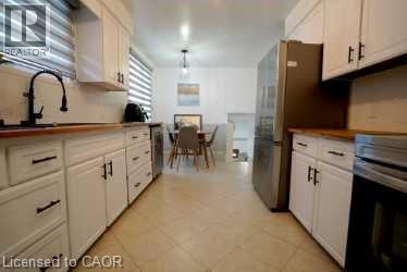 Kitchen with white cabinets, appliances with stainless steel finishes, pendant lighting, and light tile patterned floors - 147 Muriel Crescent, London, ON - Indoor Photo Showing Kitchen