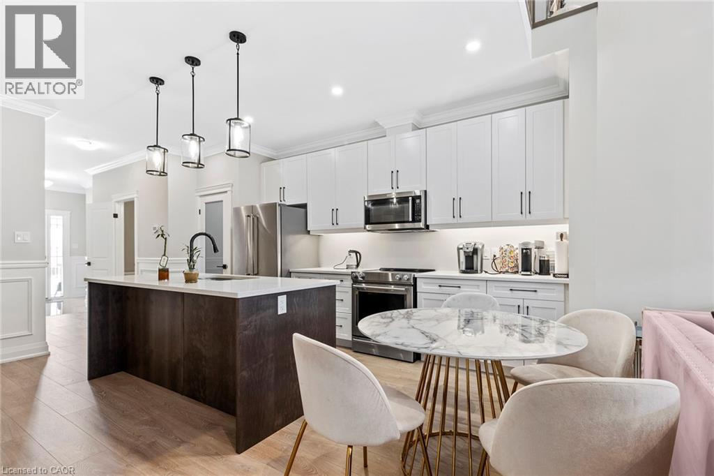 Kitchen with stainless steel appliances, a kitchen island with sink, a decorative wall, pendant lighting, and wainscoting - 24 Tamarack Way, Simcoe, ON - Indoor