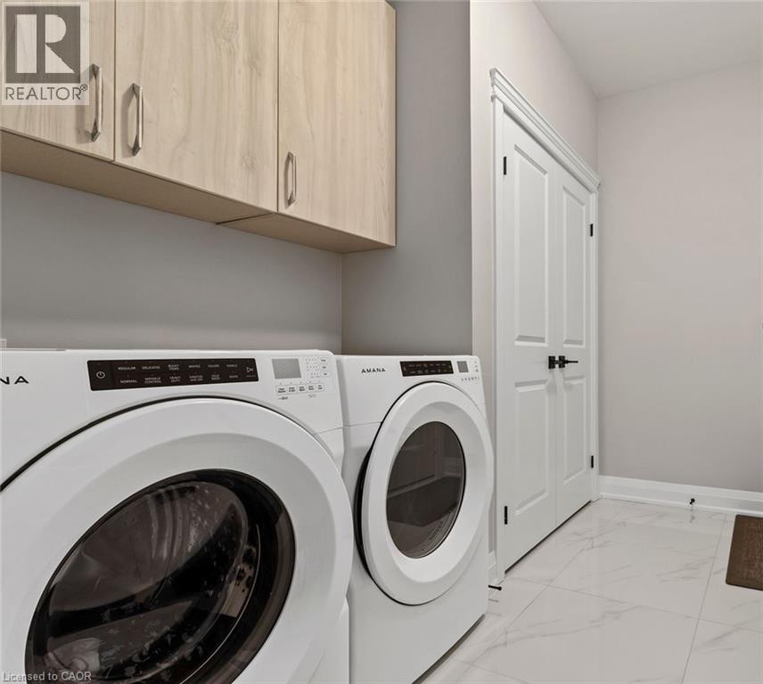 Laundry area featuring light marble finish floors, cabinet space, and washer and dryer - 24 Tamarack Way, Simcoe, ON - Indoor Photo Showing Laundry Room