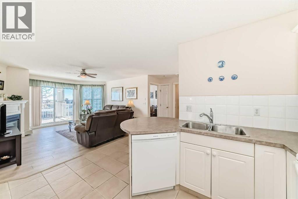 111, 6900 Hunterview Drive Nw, Calgary, AB - Indoor Photo Showing Kitchen With Fireplace With Double Sink