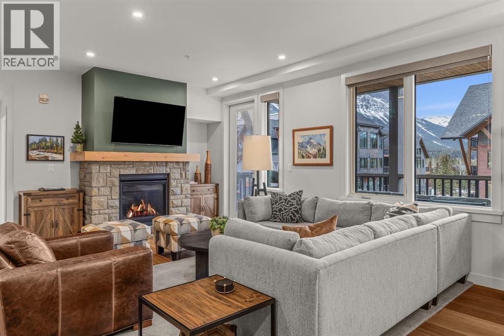 Stone surround, gas fireplace - 313, 1408 Spring Creek Gate, Canmore, AB - Indoor Photo Showing Living Room With Fireplace
