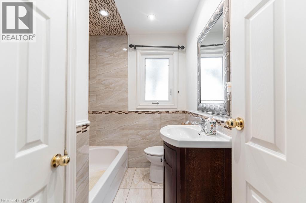 Bathroom with tile walls, recessed lighting, toilet, a bathing tub, and vanity - 854 West 5Th Street, Hamilton, ON - Indoor Photo Showing Bathroom
