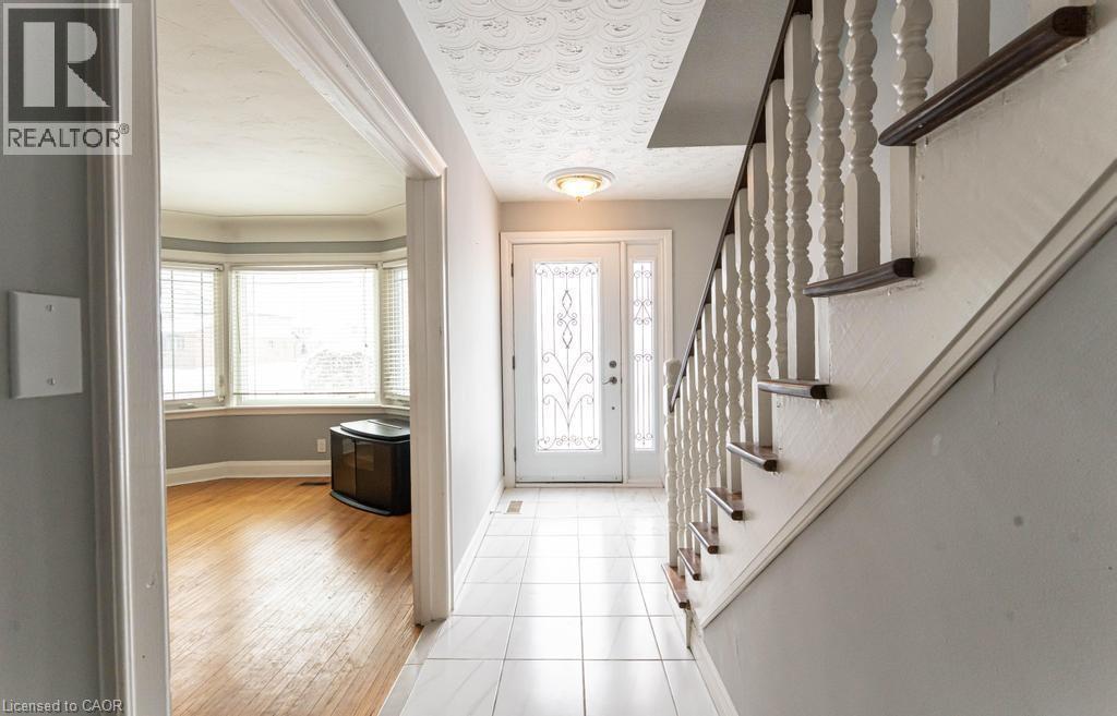Foyer featuring baseboards, stairway, a textured ceiling, and light tile patterned flooring - 854 West 5Th Street, Hamilton, ON - Indoor Photo Showing Other Room