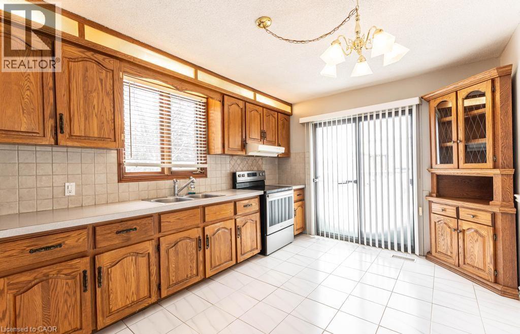 Kitchen with a sink, brown cabinets, light countertops, and electric stove - 854 West 5Th Street, Hamilton, ON - Indoor Photo Showing Kitchen With Double Sink