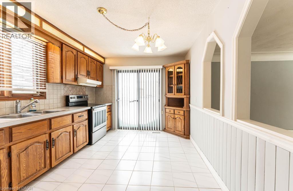 Kitchen with under cabinet range hood, a sink, light countertops, stainless steel electric range, and pendant lighting - 854 West 5Th Street, Hamilton, ON - Indoor Photo Showing Kitchen With Double Sink