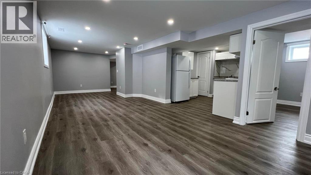 Below grade area with freestanding refrigerator, dark wood-style floors, and recessed lighting - 29 Birchcliffe Crescent Unit# 2, Hamilton, ON - Indoor