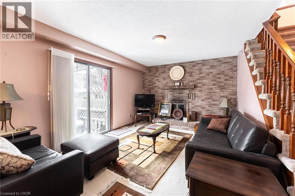 Living area with a textured ceiling, brick wall, and a fireplace - 5 Charing Drive, Hamilton, ON - Indoor Photo Showing Living Room With Fireplace