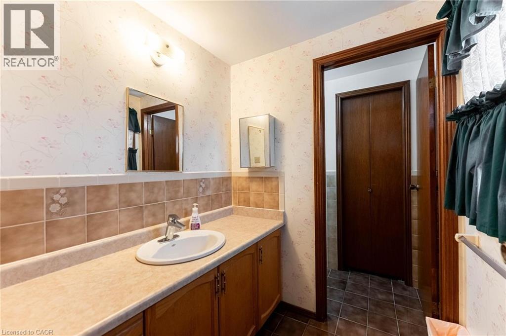 Full bathroom featuring wallpapered walls, vanity, and dark tile patterned floors - 5 Charing Drive, Hamilton, ON - Indoor Photo Showing Bathroom
